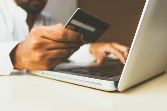 Shopper holding a card while paying online on a laptop