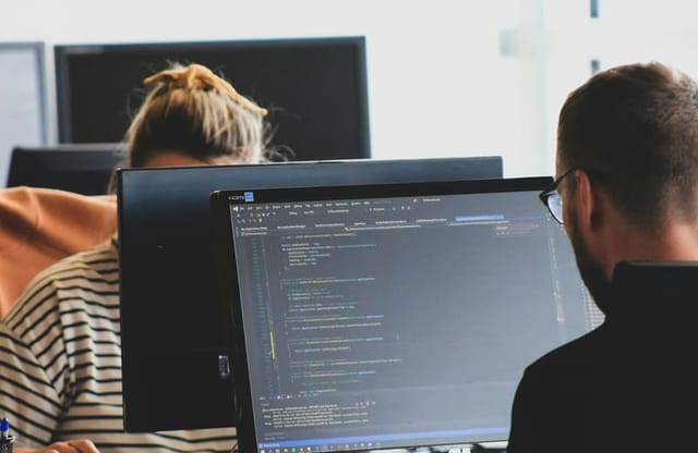 Two developers working on code at their monitors