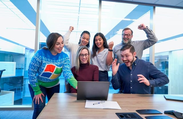 A team celebrating around a laptop